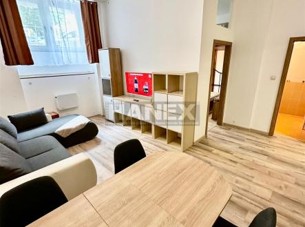 Světlý obývací pokoj s parketovou podlahou a moderním nábytkem, prostorný interiér doplněný velkými okny a neutrálními tóny stěn. | Prodej bytu, 2+1, 47 m²
