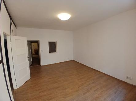Obývací pokoj s parketovou podlahou, světlé stěny a velká okna. | Pronájem bytu, atypický, 67 m²