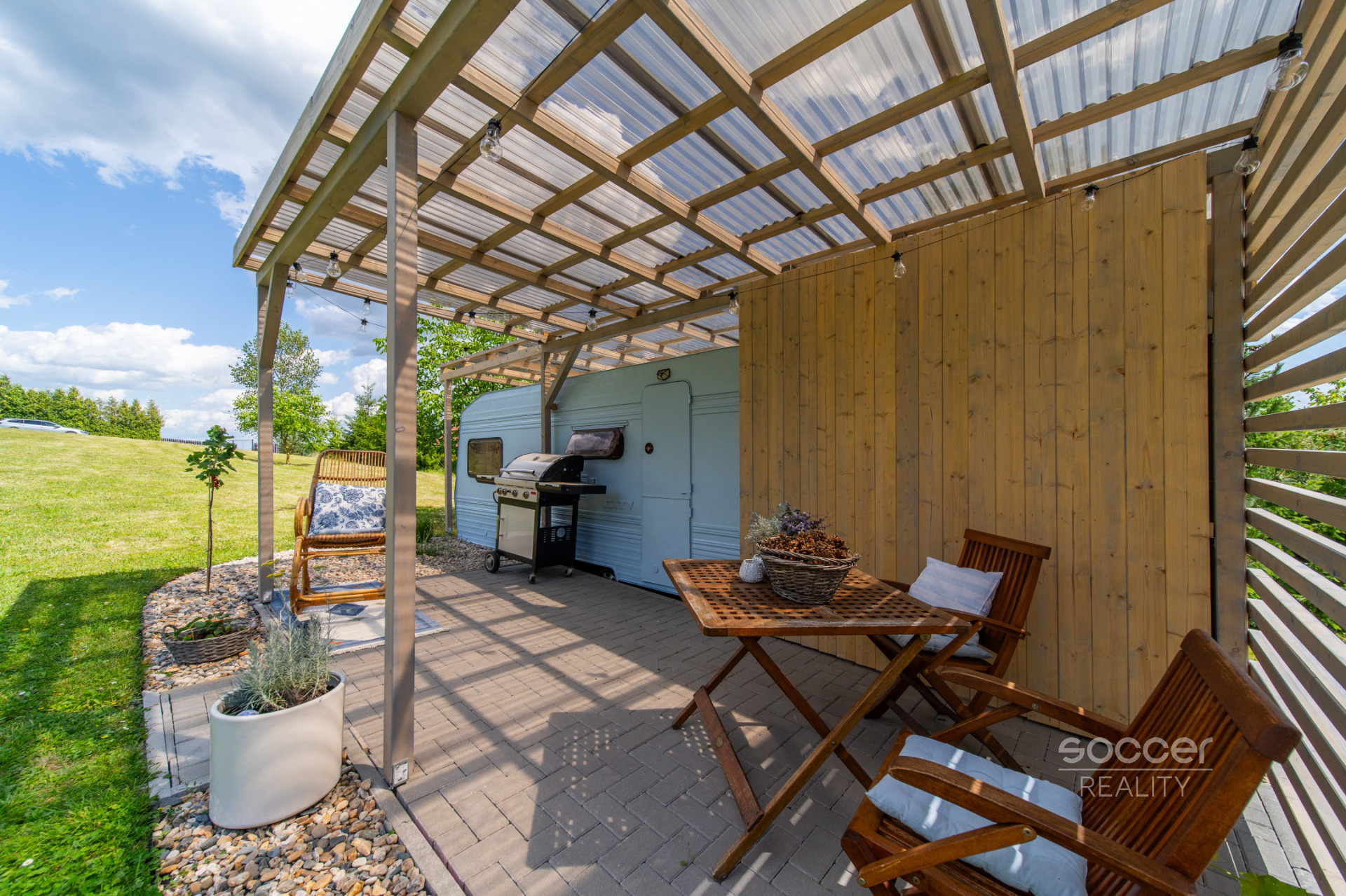 Příjemná venkovská zahrada s rekreačním karavanem a terasou.