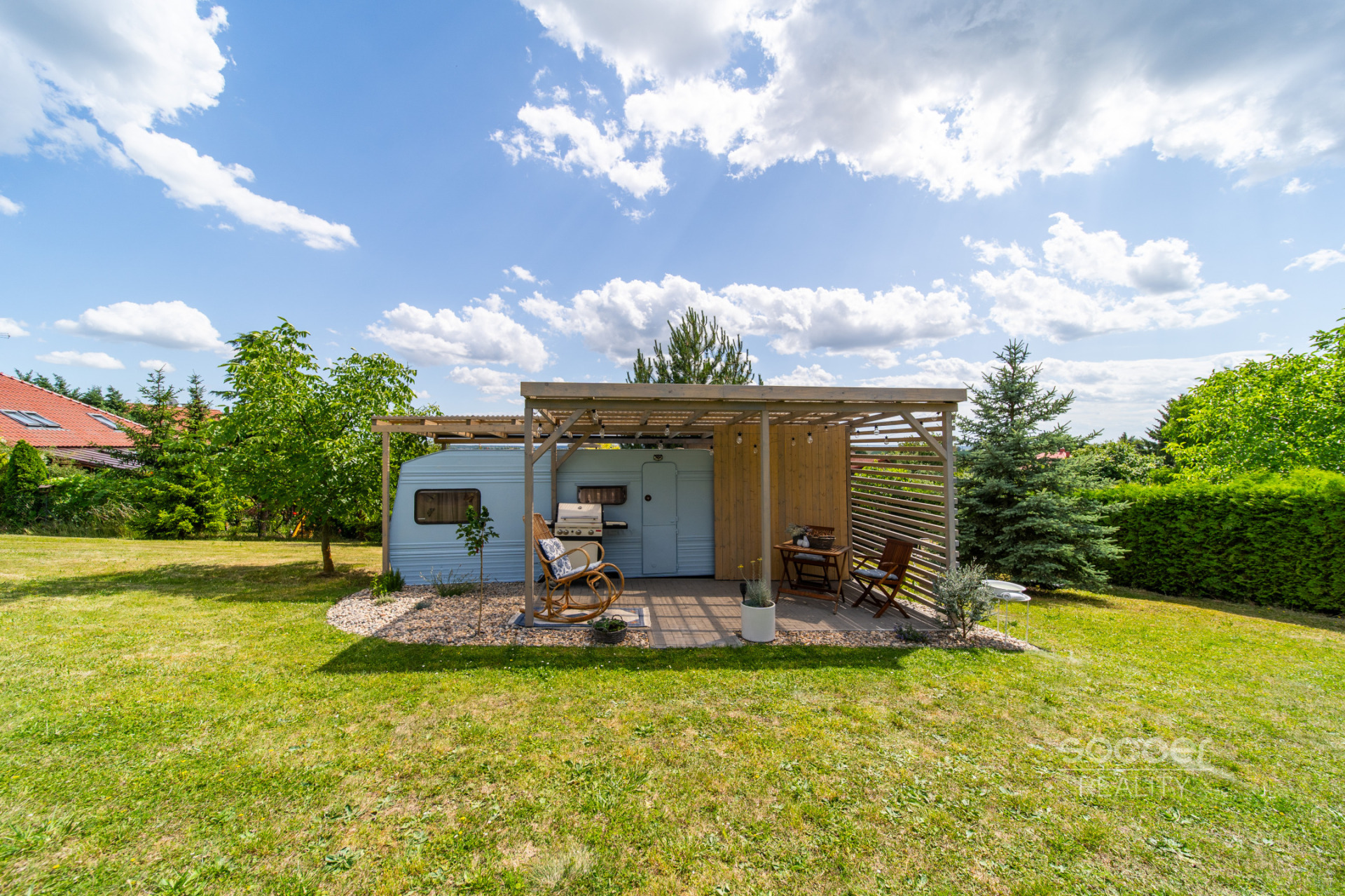 Příjemná venkovská zahrada s rekreačním karavanem a terasou.