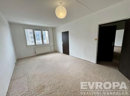 Prostorný obývací pokoj s kobercovou podlahou, velkými okny a moderní výmalbou, připravený pro personalizaci a renovaci. | Prodej bytu, 2+1, 62 m²