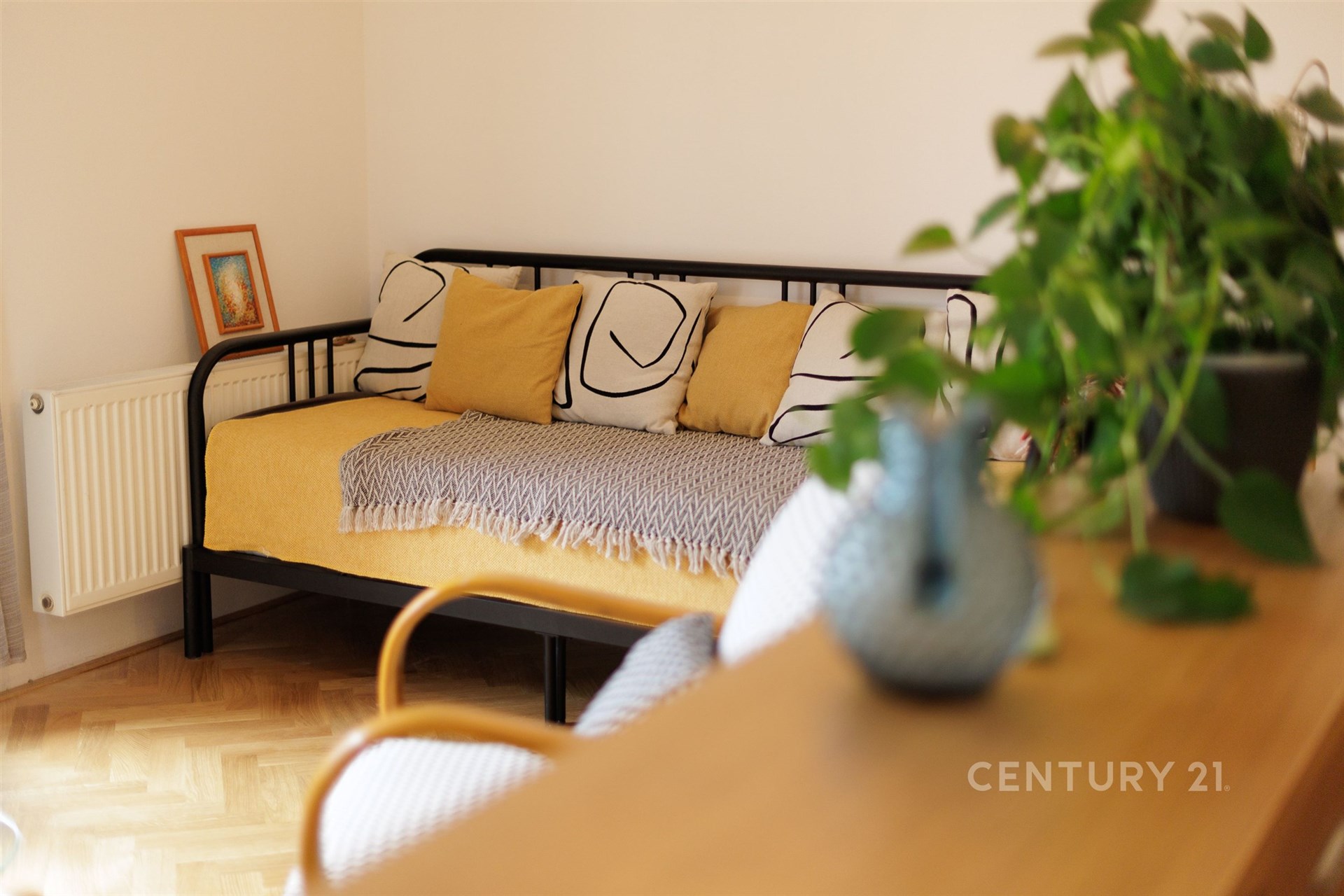 Světlý obývací pokoj s parketovou podlahou, moderním nábytkem a velkými okny vytváří útulnou atmosféru pro relaxaci a odpočinek.