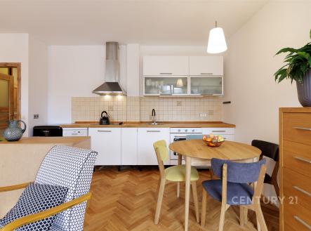 Kuchyň s parketovou podlahou, moderní bílá linka, vestavěné spotřebiče, světlé dřevo nábytku, kytka na komodě. | Pronájem bytu, 2+kk, 57 m²