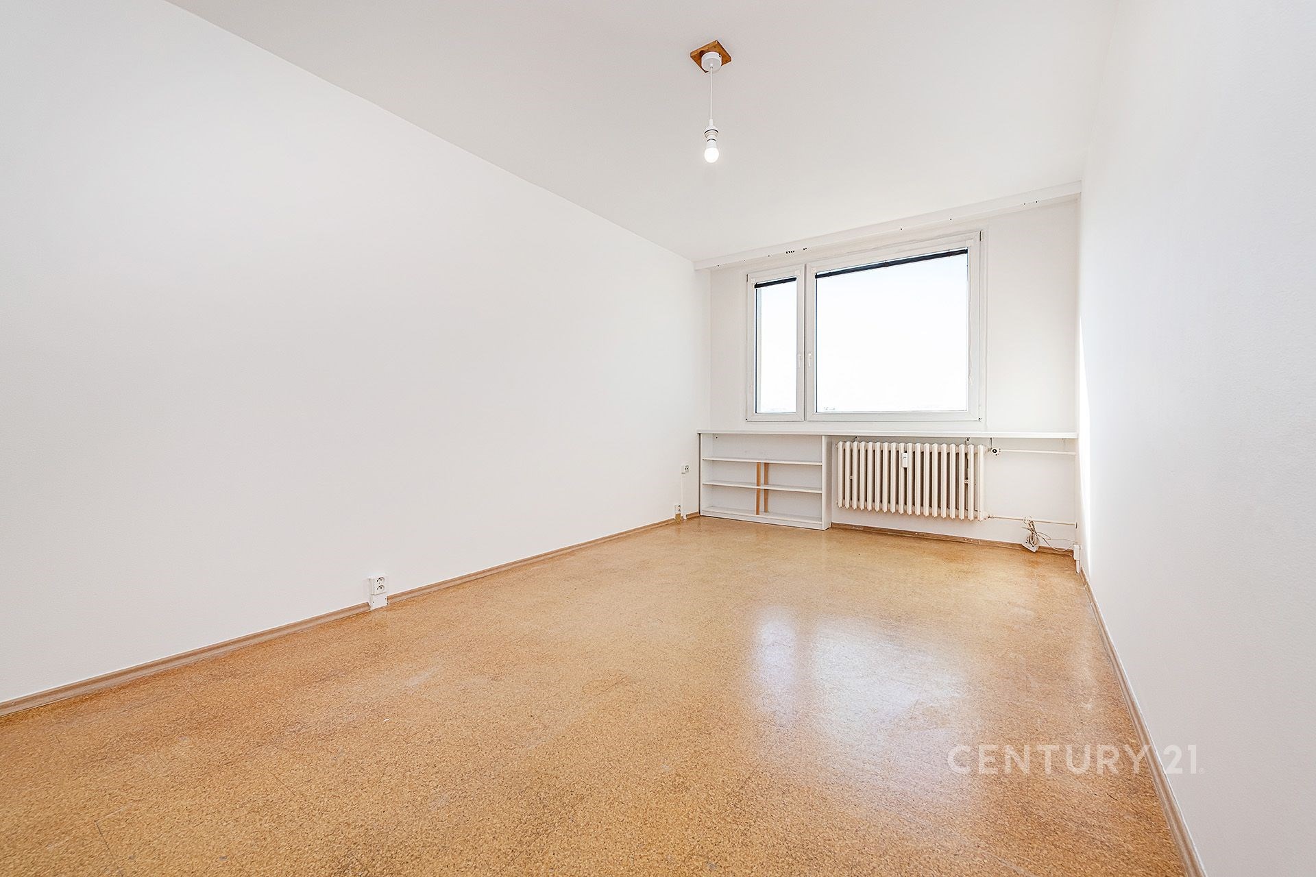 Prázdná ložnice s bílými stěnami, světlé lino, velká okna, topení u okna, dostatek přirozeného světla, moderní vzhled, čistý prostor