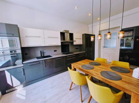 Moderní kuchyň s parketovou podlahou, vestavěné spotřebiče, dřevěný jídelní stůl, světlý interiér, stylové osvětlení. | Prodej bytu, 2+1, 62 m²