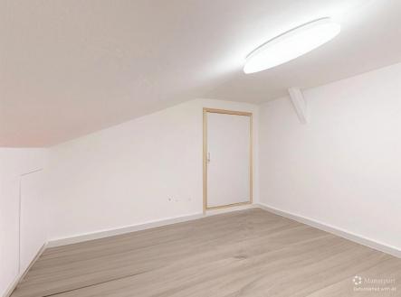 Prostorný pokoj v podkroví a bílými stěnami, ideální pro kreativní využití nebo ložnici. | Prodej bytu, 1+1, 36 m²