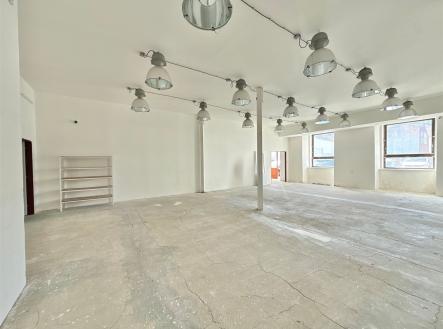Prostorný nebytový prostor s betonovou podlahou, velkými okny a moderními svítidly, vhodný pro podnikání nebo kanceláře. | Pronájem - kanceláře, 365 m²