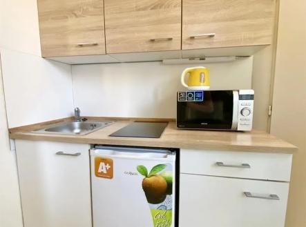 kuchyně s deformace, světle hnědé skříně, mikrovlnná trouba, a myčka | Pronájem bytu, 1+1, 21 m²