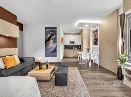 Prostorný obývací pokoj s moderní kuchyní, dřevěná podlaha, velká okna, světlý interiér, elegantní dekorace, integrované úložné prostory. | Prodej bytu, 2+kk, 58 m²