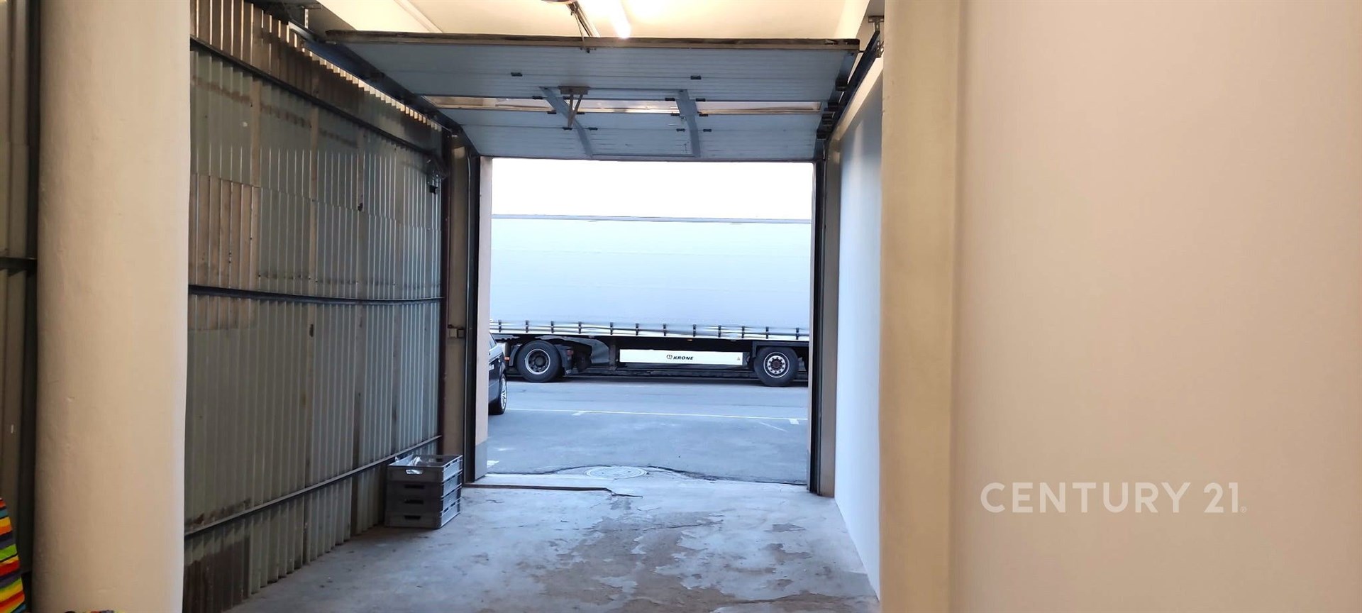 Garáž se světlým interiérem, betonovou podlahou a rozměrnými vraty, ideální pro parkování nebo skladování, v dobrém technickém stavu.