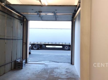 Garáž se světlým interiérem, betonovou podlahou a rozměrnými vraty, ideální pro parkování nebo skladování, v dobrém technickém stavu. | Pronájem - skladovací prostor, 33 m²