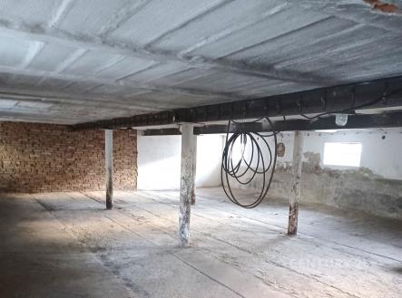 Průmyslový prostor s betonovou podlahou, cihlovou zdí a železnými nosníky, vhodný pro skladování nebo dílnu. | Pronájem - skladovací prostor, 288 m²