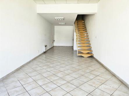 Prostorná místnost s dlažbou, krbovými kamny a moderním schodištěm nabízí velký potenciál pro obchodní prostory. | Pronájem - obchodní prostor, 58 m²