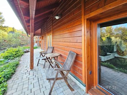 Venkovní terasa s dřevěným obložením, dlažbou a zahradním nábytkem nabízí klidný prostor pro relaxaci. | Prodej - dům/vila, 131 m²
