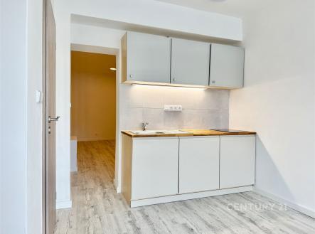 Kompaktní kuchyň se světlou dřevěnou podlahou, moderními skříňkami a světlými dlaždicemi nabízí praktický a stylový prostor v rekonstruovaném bytě. | Pronájem bytu, 2+kk, 32 m²