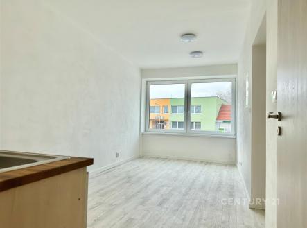 Světlý obývací pokoj s velkými okny, laminátovou podlahou a moderním designem, ideální pro útulné bydlení v rekonstruovaném bytě. | Pronájem bytu, 2+kk, 32 m²