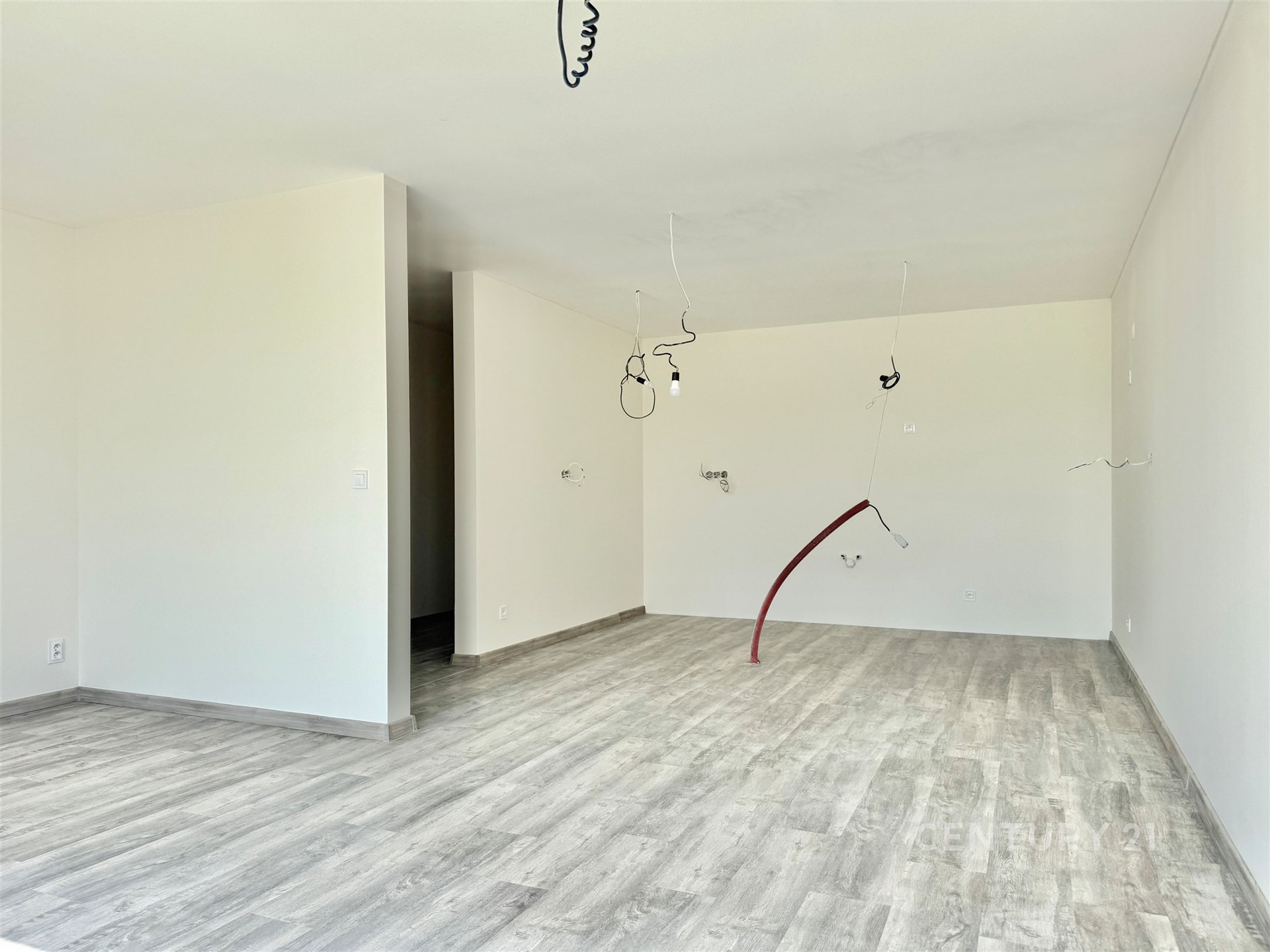 Prostorný obývací pokoj s moderní laminátovou podlahou a bílými stěnami, ideální pro vytvoření útulného rodinného prostředí.