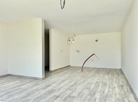 Prostorný obývací pokoj s moderní laminátovou podlahou a bílými stěnami, ideální pro vytvoření útulného rodinného prostředí. | Prodej - dům/vila, 107 m²