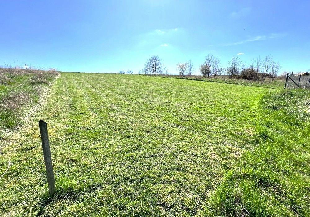 Stavební pozemek s rovinným terénem a upraveným trávníkem, ideální pro výstavbu. Klidná lokalita obklopená zelení, skvělá investiční příležitost.