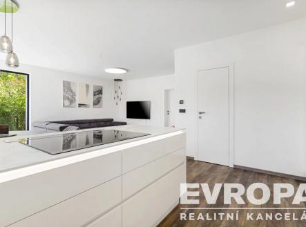 kuchyně s bílé skříně, televize, dřevěná podlaha, závěsné osvětlení, a ploché panelové skříňky | Pronájem - dům/vila, 147 m²