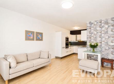 Světlý obývací pokoj s parketovou podlahou, moderní kuchyňskou linkou a dekorativní stěnou, útulný a otevřený prostor. | Pronájem bytu, 2+kk, 53 m²