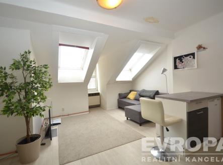 Podkrovní obývací pokoj s moderním nábytkem, světlou laminátovou podlahou a velkými střešními okny poskytujícími dostatek přirozeného světla. | Pronájem bytu, 2+kk, 49 m²