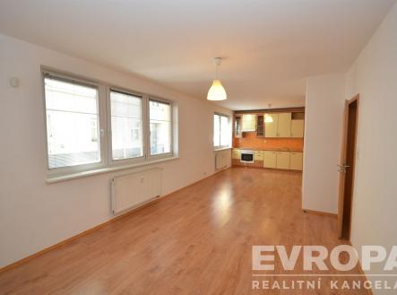 Světlý obývací pokoj s parketovou podlahou a velkými okny, moderní kuchyň se světlým dřevem a vestavěnými spotřebiči. | Pronájem bytu, 2+kk, 73 m²