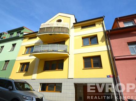 Fasáda rekonstruovaného bytového domu se žlutými stěnami, dřevěnými okny a prostorným balkónem, umístěná v městském prostředí. | Pronájem bytu, 2+kk, 73 m²