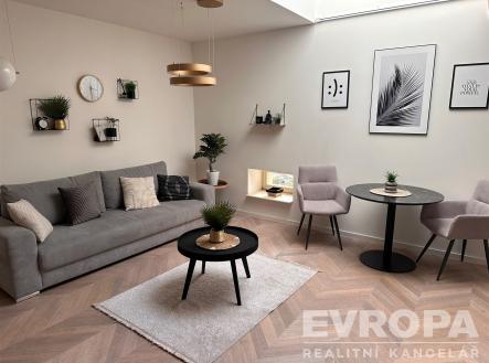 Světlý obývací pokoj se parketovou podlahou, velká okna, moderní nábytek, stylové dekorace, pohodlná sedací souprava a jídelní kout. | Pronájem bytu, 2+kk, 44 m²