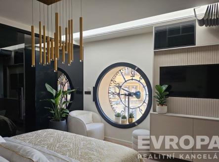 Stylová ložnice s moderní dekorací, kulaté okno, světlá výmalba, vestavěné skříně, dřevěné prvky a moderní svítidla. | Pronájem bytu, atypický, 120 m²