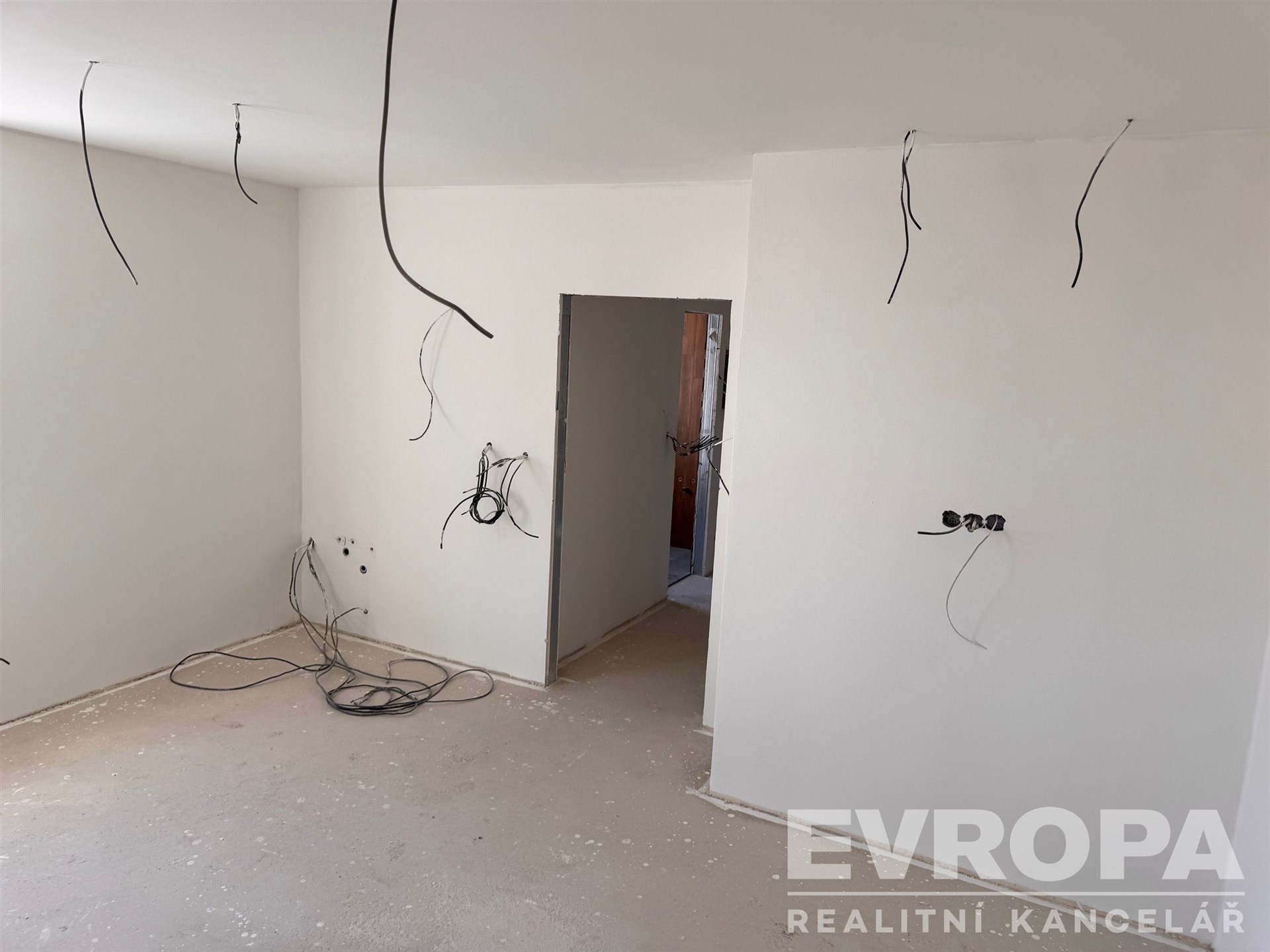 Prázdná místnost s nedokončenou betonovou podlahou a bílými zdmi, příprava na elektroinstalaci, moderní rekonstrukce, čistý design