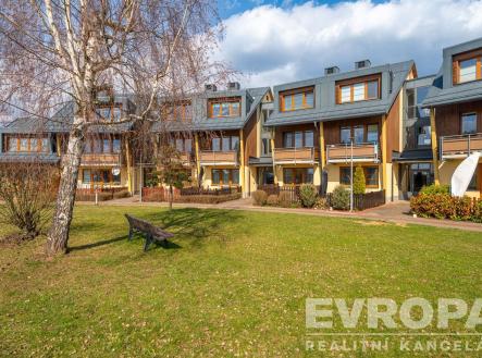 Moderní řadové domy s dřevěnými fasádami a velkými okny, obklopené zeleným trávníkem, nabízejí klidné bydlení v přírodní lokalitě. | Prodej bytu, 2+kk, 51 m²