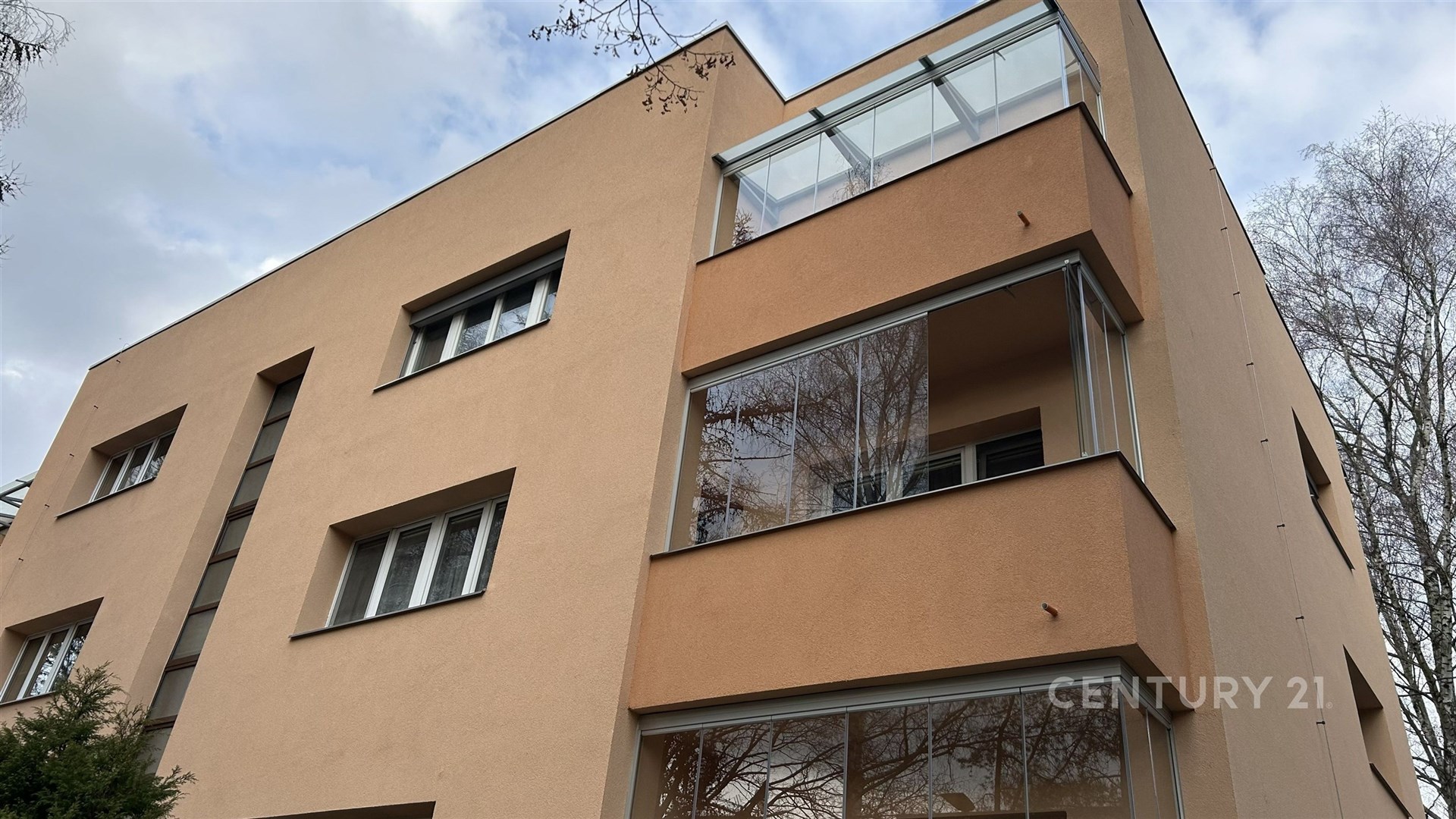 Fasáda bytového domu s moderními okny, zateplená fasáda, balkony s prosklením, klidná lokalita, velmi dobrý stav.