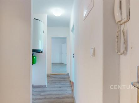 Úzká chodba s laminátovou podlahou, moderním osvětlením a vestavěným bojlerem, vede k dalším pokojům v rekonstruovaném bytě. | Prodej bytu, 3+1, 73 m²