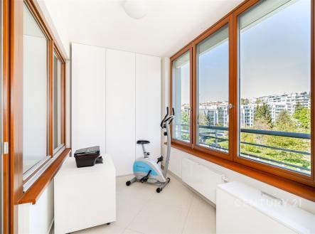Světlá lodžie s velkými okny a dlažbou nabízí výhled na městskou krajinu, moderní design podtrhují vestavěné skříně a čisté linie. | Prodej bytu, 3+kk, 105 m²