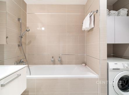 Moderní koupelna s novými obklady, vanou a pračkou. Světlé dlažby a čistý design zvyšují pocit prostornosti a komfortu. | Prodej bytu, 3+kk, 105 m²