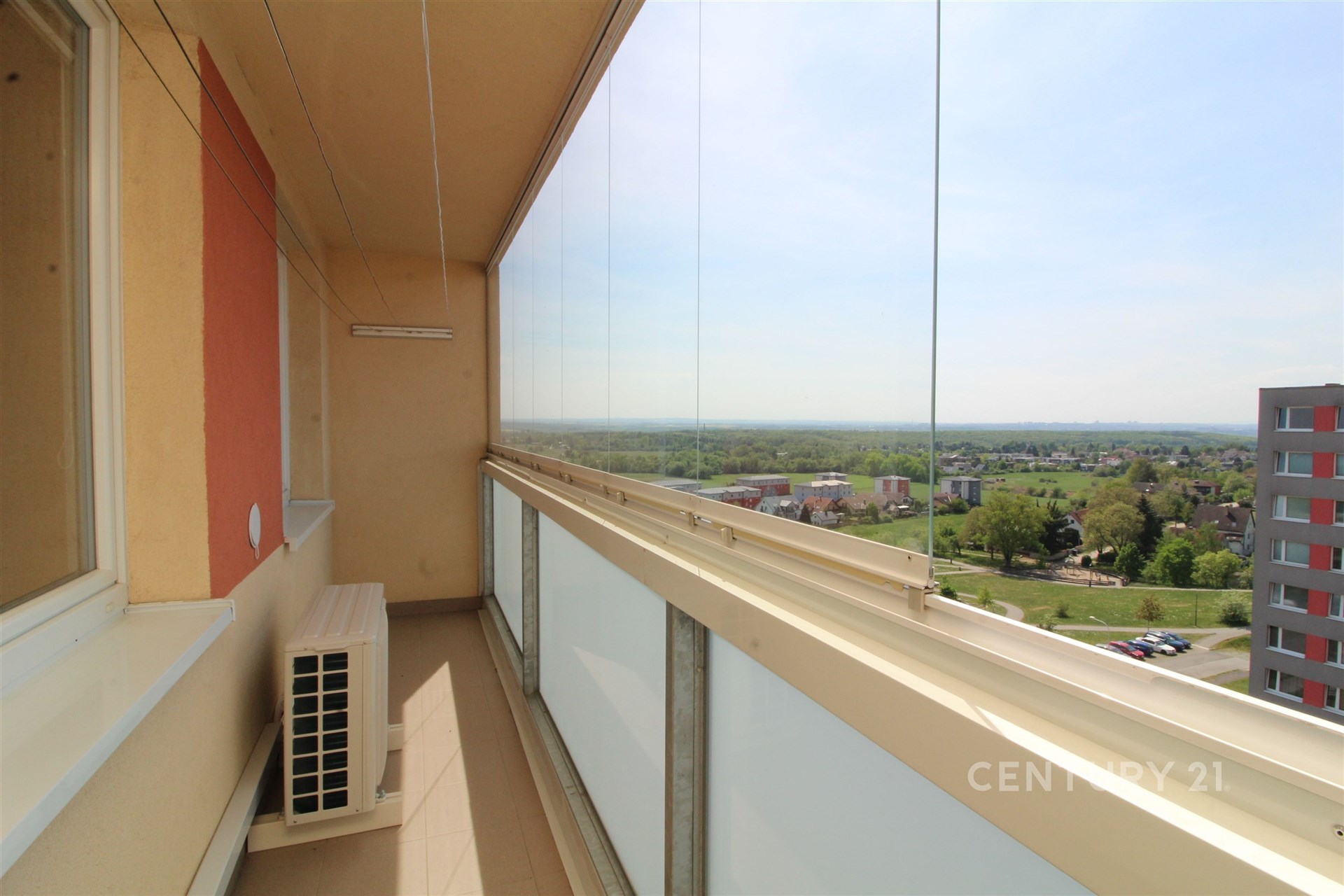 Zasklená lodžie s panoramatickým výhledem, dlažba na podlaze, moderní zasklení, ideální pro relaxaci.