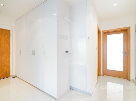 Vstupní hala s vestavěnými skříněmi, bílými stěnami a dřevěnými dveřmi, dlažba na podlaze, moderní a světlý styl. | Prodej bytu, 3+kk, 105 m²