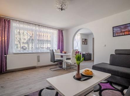 Světlý obývací pokoj s moderní sedací soupravou, parketovou podlahou, velkými okny a elegantním nábytkem v rekonstruovaném bytě. | Prodej - dům/vila, 71 m²
