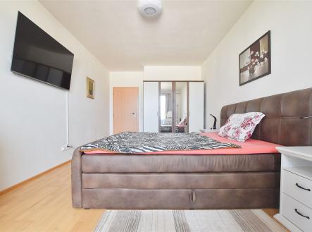 Prostorná ložnice s parketovou podlahou, velkou postelí a moderním vybavením. Disponuje velkými vestavěnými skříněmi a minimalistickým stylem. | Prodej bytu, 2+kk, 62 m²