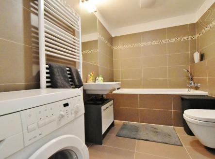 vana s toaleta, radiátor, stěna dlaždic, kachličková podlaha, a pračka / sušička | Pronájem bytu, 1+kk, 39 m²