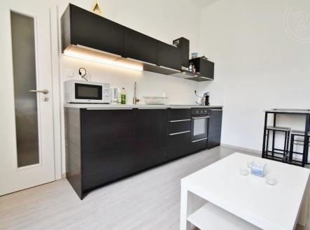 kuchyně s mikrovlnná trouba, deformace, dřevěná podlaha, a černé skříňky | Pronájem bytu, 2+kk, 42 m²