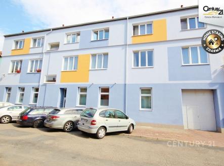 Tmavě modrá fasáda bytového domu s velkými okny a parkovacím místem na ulici, moderní vzhled a zrekonstruovaná úprava. | Pronájem - kanceláře, 17 m²