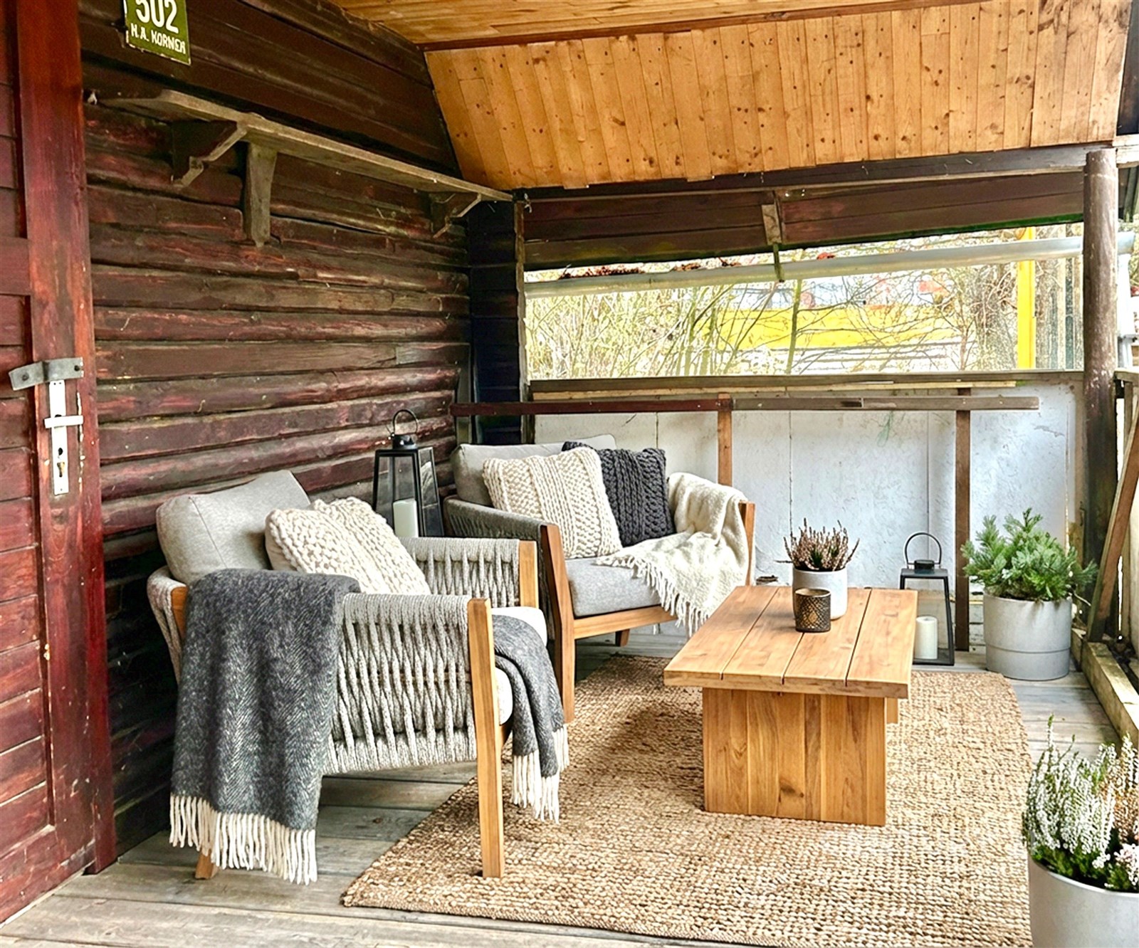 Krytá terasa s dřevěným stropem a stěnami, vybavená pohodlnými křesly a dřevěným stolkem, útulné venkovní posezení, přírodní dekorace.