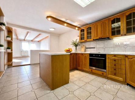 Prostorná kuchyň s dřevěnými skříňkami, dlažbou a vestavěnou troubou. Velká okna v obývacím pokoji zajišťují světlost interiéru. | Pronájem - dům/vila, 135 m²