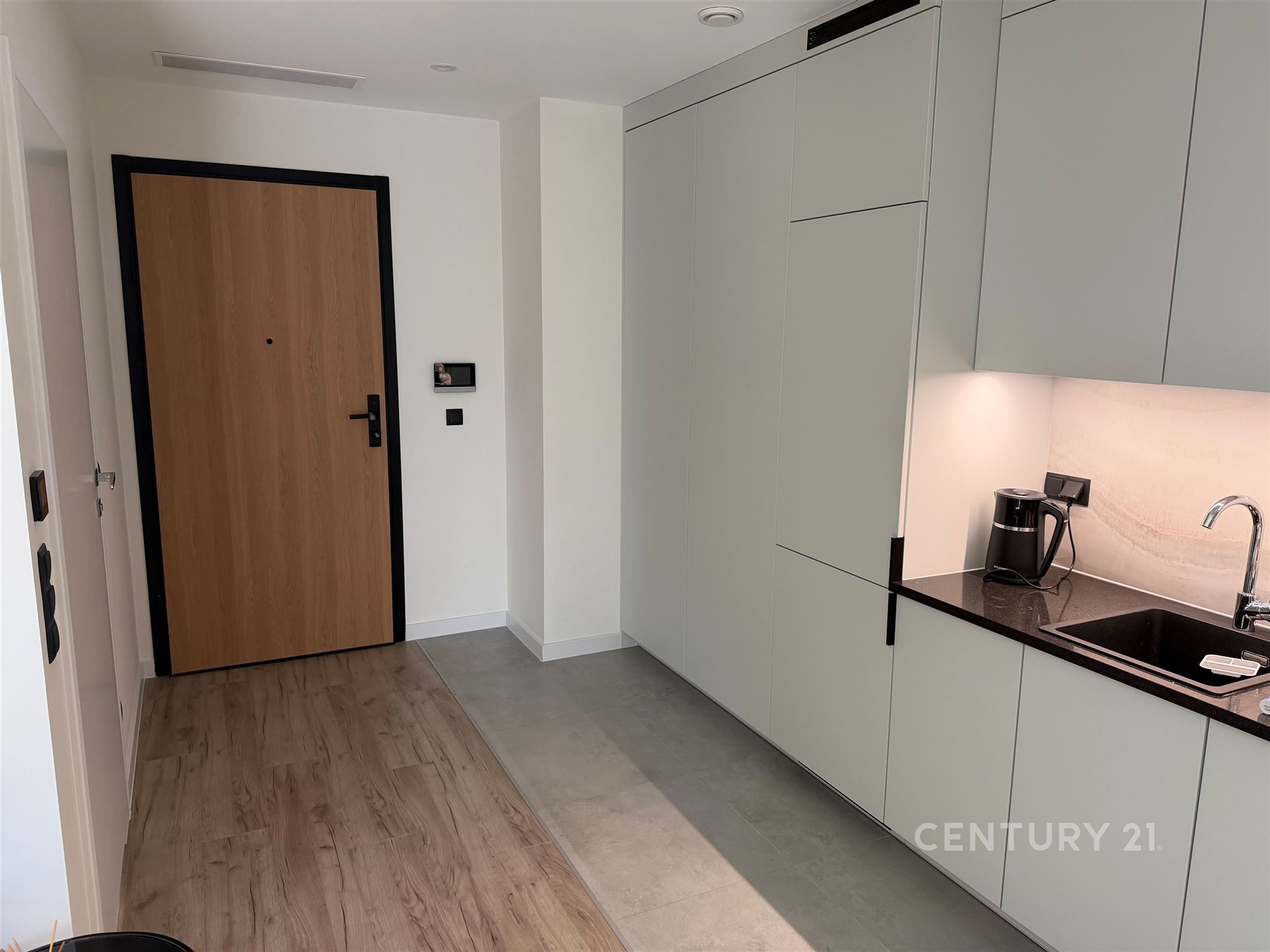 Vstupní hala s moderní kuchyňskou linkou, parketová podlaha, vestavěné skříně a světlé povrchy vytvářejí stylový a funkční prostor.