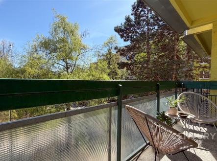 Prostorný balkon s výhledem na zeleň, moderní kovové zábradlí, pohodlná venkovní sezení, slunná orientace. | Prodej bytu, 1+kk, 32 m²