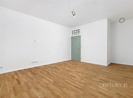 Prázdný obývací pokoj s parketovou podlahou, bílými stěnami a pastelovými dveřmi, minimalistický design, připravený k okamžitému nastěhování. | Prodej bytu, 4+kk, 104 m²