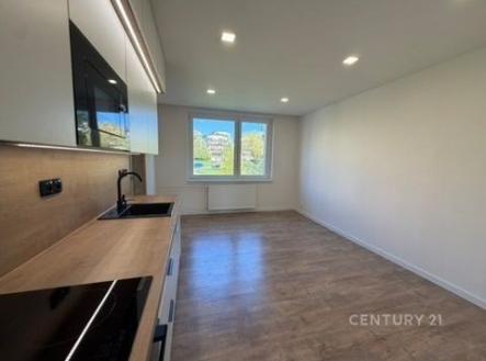 Moderní kuchyň s parketovou podlahou, velkými okny a vestavěnými spotřebiči, vytváří světlý a funkční prostor. | Pronájem bytu, 3+kk, 62 m²