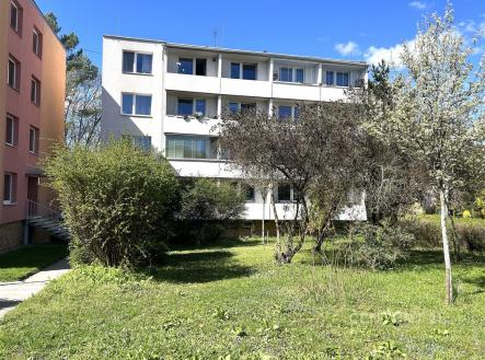 Čtyřpodlažní bytový dům s bílou fasádou, obklopený zeleným trávníkem a stromy, umístěný na klidném místě v rezidenční čtvrti. | Prodej bytu, 2+1, 54 m²